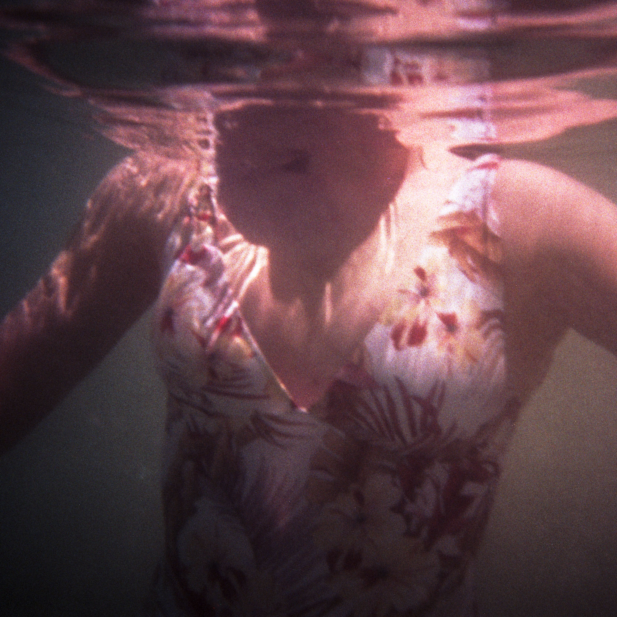 Pale figures in pink-toned underwater light at Manyana — 35mm Fuji C200